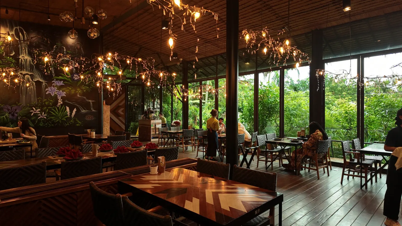 Indoor dining tables with windows looking onto tropical greenery