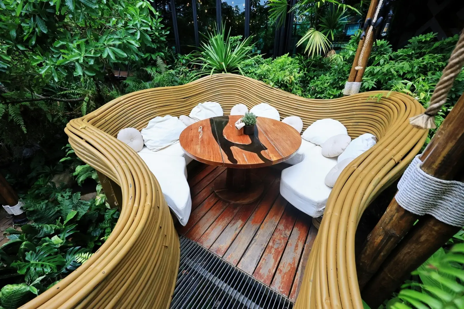 Round dining table and white cushions inside a curved Monkey Nest seat