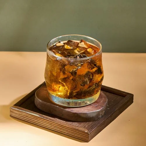 Amber iced oolong tea in a glass on a wooden tray