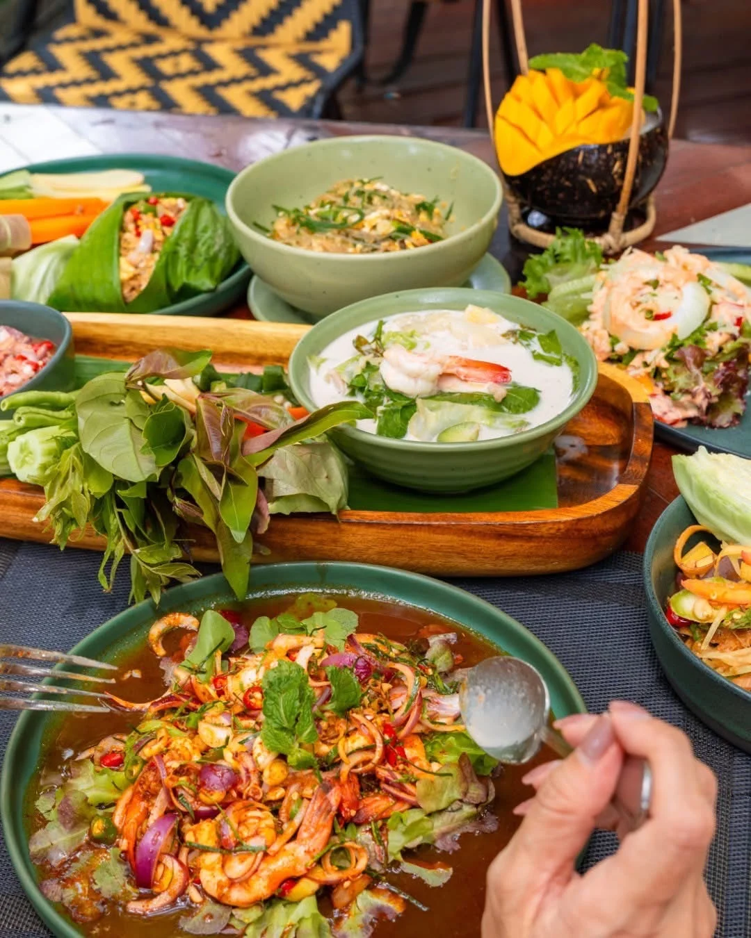 Prawn dish in the foreground with coconut soup and vegetables on the table