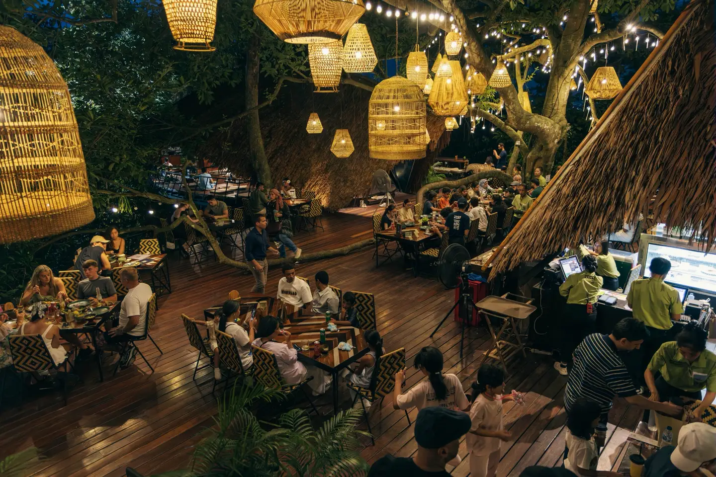 Dining room with woven lamps, wooden flooring and occupied tables
