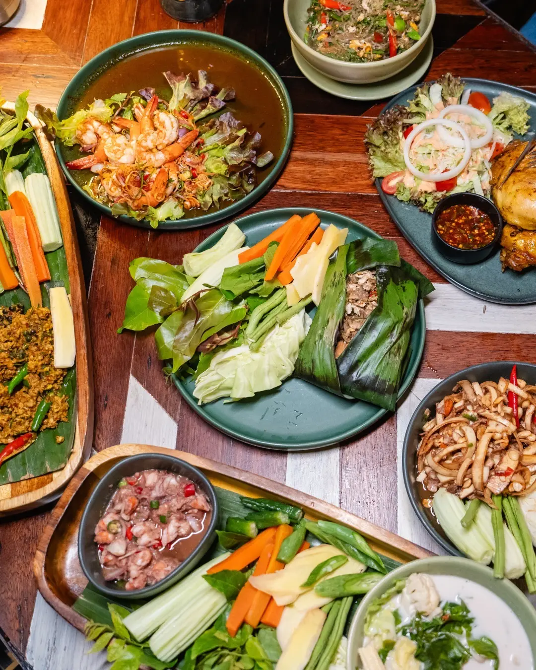Overhead view of Thai dishes with prawns, vegetables and leaf-wrapped food